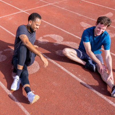 Two runners stretching, with Evamor water